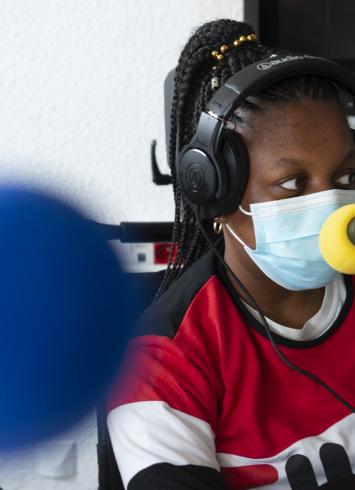 Le visuel représente une des jeunes filles qui a participé au projet de podcast, face à son micro.
